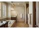 Elegant bathroom featuring a soaking tub, walk-in shower, and neutral tiling at 15179 W Washburn Ave, Lakewood, CO 80228