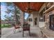 Covered patio boasts stone accents, a ceiling fan, and comfortable seating with a view of the trees at 2094 Lost Canyon Ranch Ct, Castle Rock, CO 80104