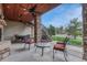 Covered patio features stone columns, ceiling fans, and outdoor seating with views of the landscaped yard at 2094 Lost Canyon Ranch Ct, Castle Rock, CO 80104