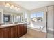 Bright bathroom featuring double sinks, large window and a separate tub and shower enclosure at 11093 Nome St, Commerce City, CO 80640