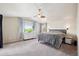Bright main bedroom featuring a ceiling fan, ensuite bathroom and large window with tree views at 11093 Nome St, Commerce City, CO 80640