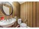 Stylish powder room with brown patterned wallpaper, a pedestal sink and an oval mirror at 6761 Mary Ct, Castle Pines, CO 80108