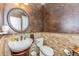 Powder room featuring stone accent wall, vanity and round mirror at 6761 Mary Ct, Castle Pines, CO 80108