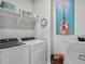 Efficient laundry room with modern washer and dryer, overhead shelves, and decorative wall art at 3453 N Gold Bug Ct, Aurora, CO 80019