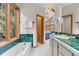 Bright bathroom boasting a soaking tub, sink with tiled countertops, and forest views at 30264 Upper Bear Creek Rd, Evergreen, CO 80439