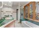 Inviting bathroom features a soaking tub, glass enclosed shower, and verdant views from the window at 30264 Upper Bear Creek Rd, Evergreen, CO 80439