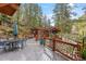 Expansive deck with dining area, rustic railings, and lush greenery offering a perfect outdoor living space at 30264 Upper Bear Creek Rd, Evergreen, CO 80439