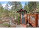 Stunning exterior view of a home nestled among trees, featuring a deck, charming railings, and landscaped walkway at 30264 Upper Bear Creek Rd, Evergreen, CO 80439