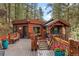 Charming log cabin featuring a spacious deck, rustic railing, and inviting blue door in a serene wooded setting at 30264 Upper Bear Creek Rd, Evergreen, CO 80439