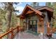 Inviting exterior featuring a gabled roof, large windows, decorative lighting, and charming deck with flower baskets at 30264 Upper Bear Creek Rd, Evergreen, CO 80439