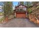 Exterior shot of home with a two-car garage, stone accents, and large windows at 30264 Upper Bear Creek Rd, Evergreen, CO 80439