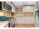 Kitchen with terracotta tile flooring, gas range, and white cabinets, bathed in natural light at 30264 Upper Bear Creek Rd, Evergreen, CO 80439