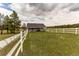 Gray barn with white fence in a grassy field at 10393 Deerfield Rd, Franktown, CO 80116