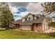 Exterior view features a brick facade, three-car garage, manicured lawn, and architectural details at 10393 Deerfield Rd, Franktown, CO 80116