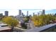 Picturesque cityscape view featuring a charming street lined with colorful trees against a backdrop of modern high-rise buildings at 701 E 24Th Ave, Denver, CO 80205