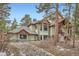 View of a residence with architectural details, featuring timber accents, and a landscaped exterior with natural rock features at 1662 Gore Dr, Larkspur, CO 80118