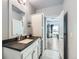 Bathroom vanity with double sinks, black countertops, white cabinets, and views into the dining area at 6320 Indian Paintbrush St # 108, Frederick, CO 80530