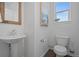 Clean half-bathroom with pedestal sink, white toilet, and modern fixtures, complemented by a framed piece of art at 8711 E Hampden Ave # 6, Denver, CO 80231