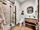 Modern bathroom featuring a glass enclosed shower, a wood vanity, and a round lighted mirror at 6736 S Flanders Ct, Aurora, CO 80016