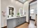 Modern bathroom featuring double sinks, sleek gray cabinetry, wood look floors, and backlit mirrors, creating a luxurious space at 6736 S Flanders Ct, Aurora, CO 80016