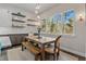 Bright dining room features a wooden table with bench, floating shelves, and large windows overlooking trees at 731 Weston Rd, Larkspur, CO 80118