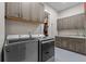 Functional laundry room boasts gray cabinetry, utility sink, and washer/dryer units at 731 Weston Rd, Larkspur, CO 80118