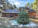 Charming exterior elevation of a home nestled among mature trees with a well-maintained lawn and partial brick facade at 18680 Arrowwood Dr, Monument, CO 80132