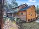 An exterior perspective of a home showcasing wood siding, brick accents, and tiered landscaping, seamlessly blending nature and design at 18680 Arrowwood Dr, Monument, CO 80132