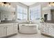 Elegant bathroom with double vanities, a soaking tub, and large windows with shutters at 21854 Tyrolite Ave, Parker, CO 80138