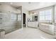 Bright bathroom featuring a glass shower and a soaking tub beneath a large window at 21854 Tyrolite Ave, Parker, CO 80138