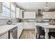 Bright kitchen showcasing white cabinetry, a stainless steel dishwasher, and stylish backsplash at 21854 Tyrolite Ave, Parker, CO 80138