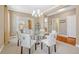 Elegant dining room with a modern glass table, white chairs, and neutral carpet at 2861 Eagle Cir, Erie, CO 80516