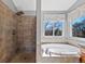 Bright bathroom featuring a walk-in shower with rainfall shower head and a soaking tub beneath a large window at 5706 S Garland Way, Littleton, CO 80123