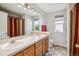 Bright bathroom featuring a double vanity, large mirror, and neutral tile flooring at 22302 Quail Run Way, Parker, CO 80138