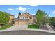 Two-story home with tan exterior, large windows, three car garage, and manicured front lawn at 22302 Quail Run Way, Parker, CO 80138