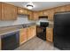 Kitchen with wood cabinets, black appliances, and vinyl flooring at 4974 E 124Th Way, Thornton, CO 80241