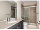 Modern bathroom with gray vanity, white countertop, and glass-enclosed shower with tiled walls at 6021 N Boston Ct, Denver, CO 80238