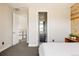 Open bedroom view with ensuite bath featuring wood accent wall detail and neutral carpet flooring at 6021 N Boston Ct, Denver, CO 80238