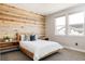 Bright bedroom featuring a stylish wood accent wall and a comfortable queen-sized bed at 6021 N Boston Ct, Denver, CO 80238