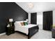 Stylish primary bedroom featuring a decorative black accent wall, plush bedding and dark curtains at 6103 S Millbrook Ct, Aurora, CO 80016