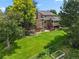 A spacious backyard featuring a lush lawn, mature trees, a garden, and a large deck area at 6895 S Norfolk St, Foxfield, CO 80016