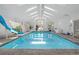 Gorgeous indoor pool with a fun blue slide and ample natural light from large windows and skylights at 6895 S Norfolk St, Foxfield, CO 80016