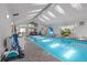 Indoor pool area featuring an in-ground pool, a slide, and natural lighting from large windows and skylights at 6895 S Norfolk St, Foxfield, CO 80016