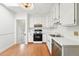 Bright kitchen featuring white cabinets, stainless steel dishwasher, and wood flooring at 810 Adams St, Denver, CO 80206