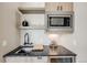 Stylish wet bar with stainless steel microwave, wooden cabinets, a dark countertop, and a sleek black faucet at 718 Emerson Gulch Rd, Boulder, CO 80302