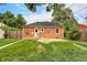 Brick home with a fenced backyard, lush green lawn, and mature trees at 2970 Leyden St, Denver, CO 80207