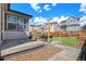 Home's backyard with seating area, grass and fence with neighboring houses under a blue sky at 3522 N Buchanan Way, Aurora, CO 80019