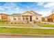 Charming ranch style home with tan siding, stone accents, landscaped yard, and covered porch at 10771 N Montane Dr, Broomfield, CO 80021