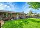Backyard featuring a lush green lawn, patio, and brick home exterior at 5175-5185 Simms Pl, Wheat Ridge, CO 80033