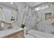 Bright bathroom with marble tiling, framed mirror, and wood vanity provides a modern aesthetic and storage at 7684 S Ingalls St, Littleton, CO 80128
